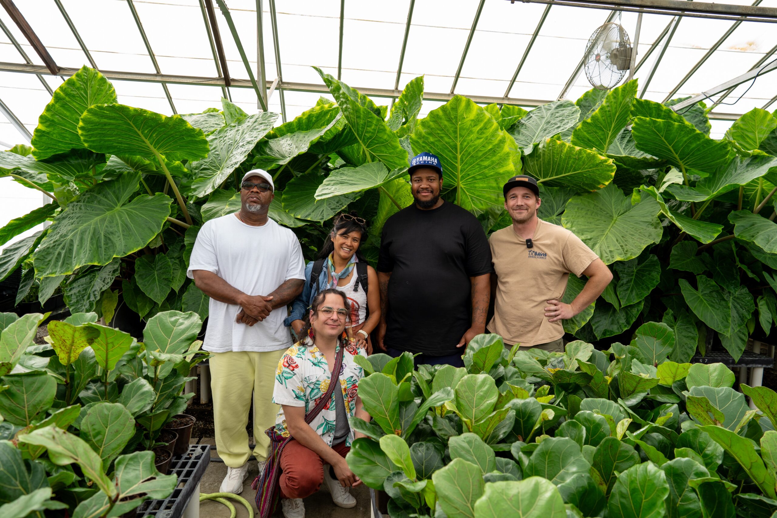 Diverse group of people standing in front of lush greenery